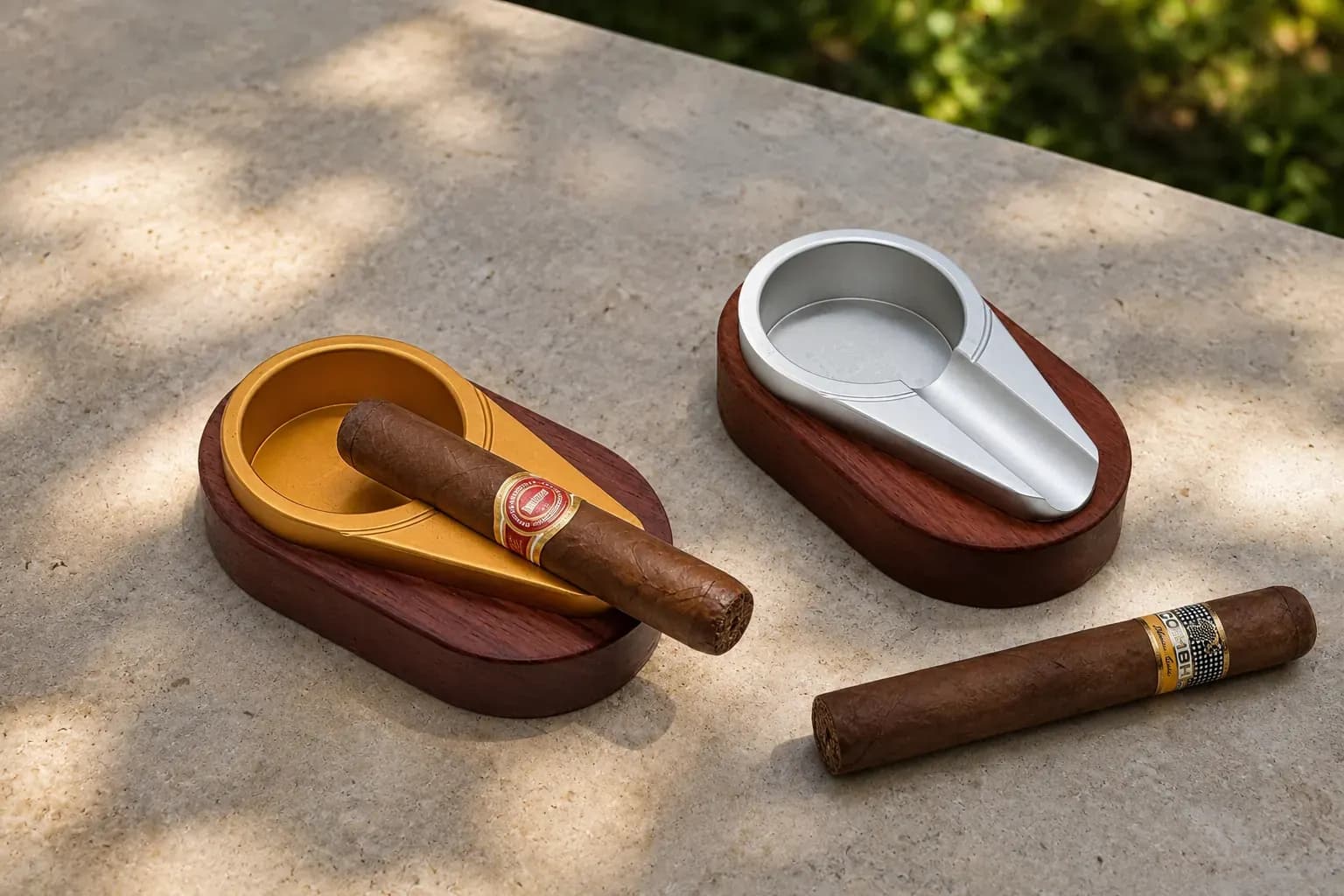 Classic Cigar Ashtray — gold and silver lounge pair Elegant gold- and silver-finish aluminium single-rest cigar ashtrays with cigars on a stone table