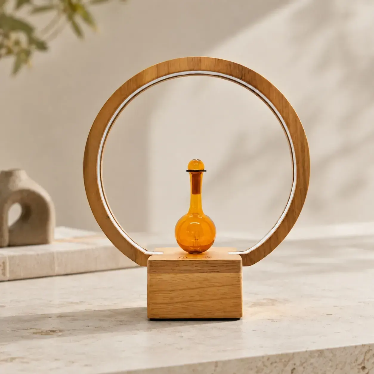 Dual-Fluid Aroma Diffuser — wood ring and amber flask Circular wood-frame dual-fluid aroma diffuser with amber glass flask and rim lighting